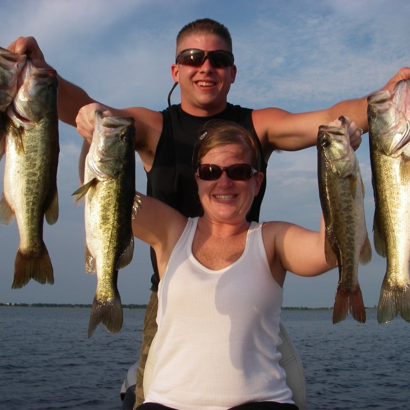 A man and a woman hold up bass they caught fishing