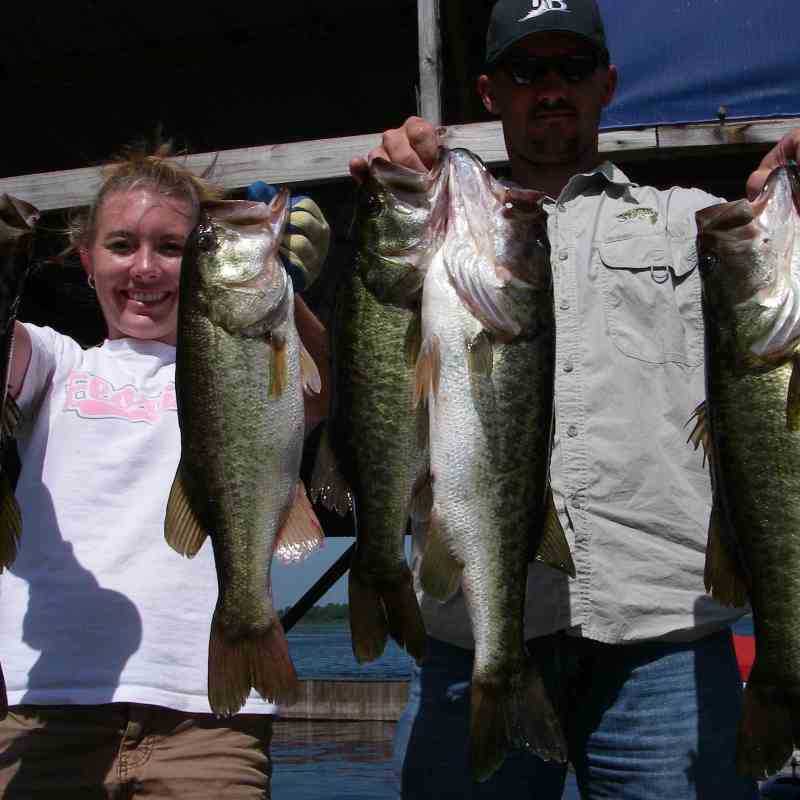 Two people hold up largemouth bass they caught