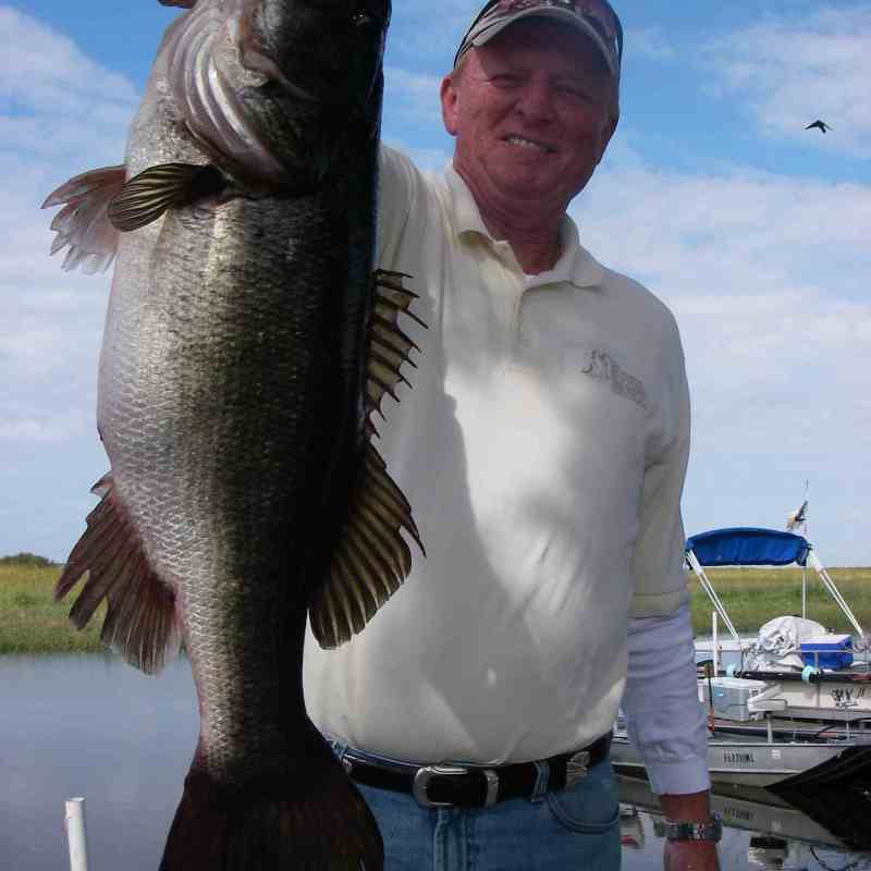 A man shows off a largemouth bass caught in Lake Toho